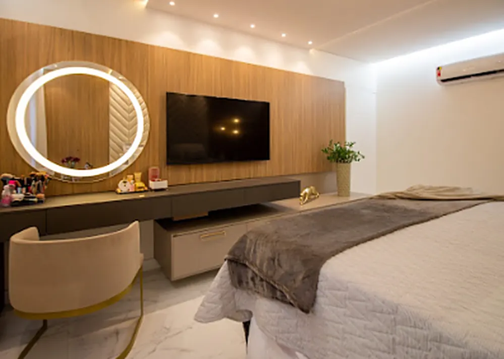 Suíte planejada com painel de TV em madeira, penteadeira e espelho iluminado.